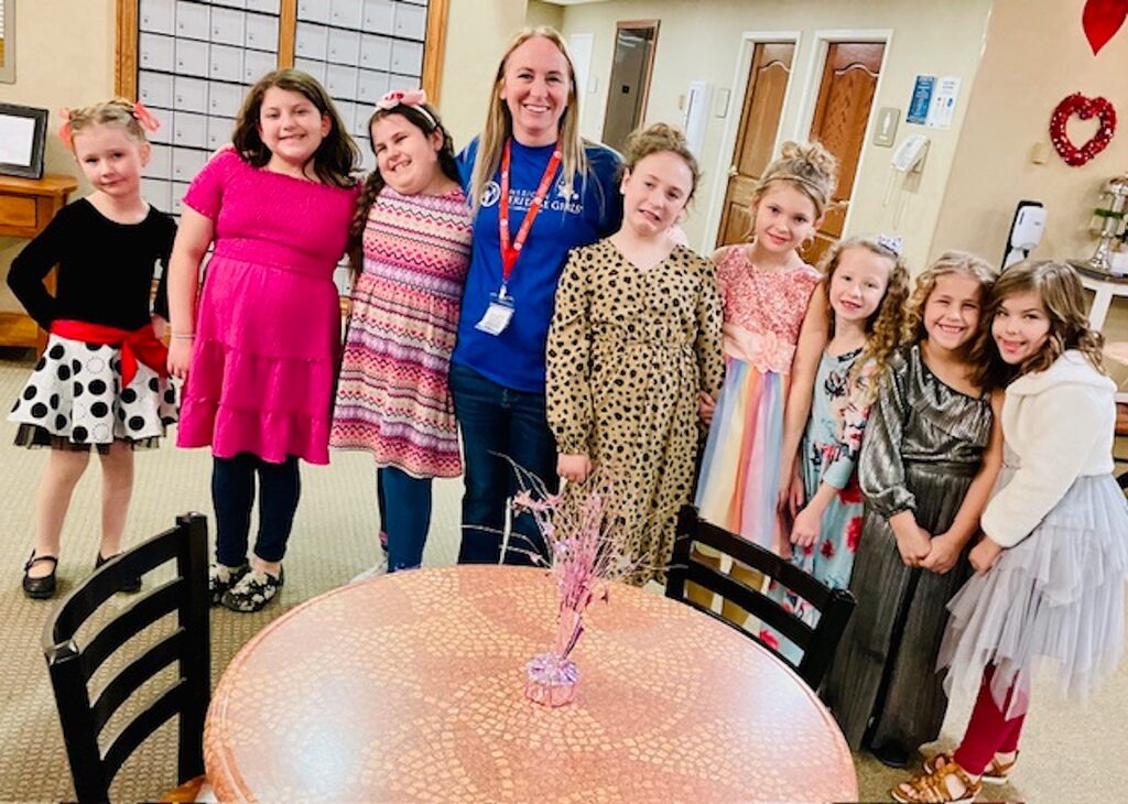 Group of young girls dressed up with Heritage employee