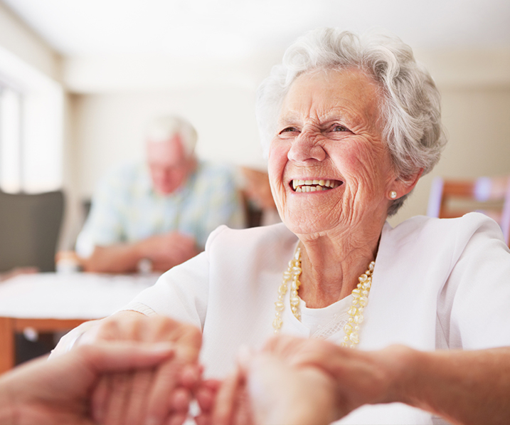 Senior woman smiling and holding hands with someone