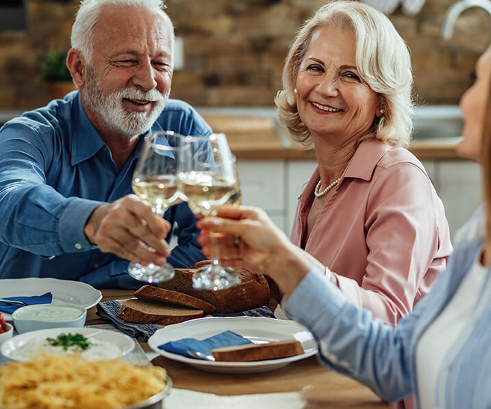 Seniors clinking wine glasses at dinner