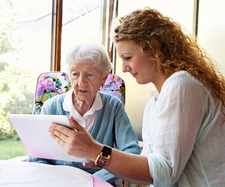 Employee showing a senior woman a tablet screen