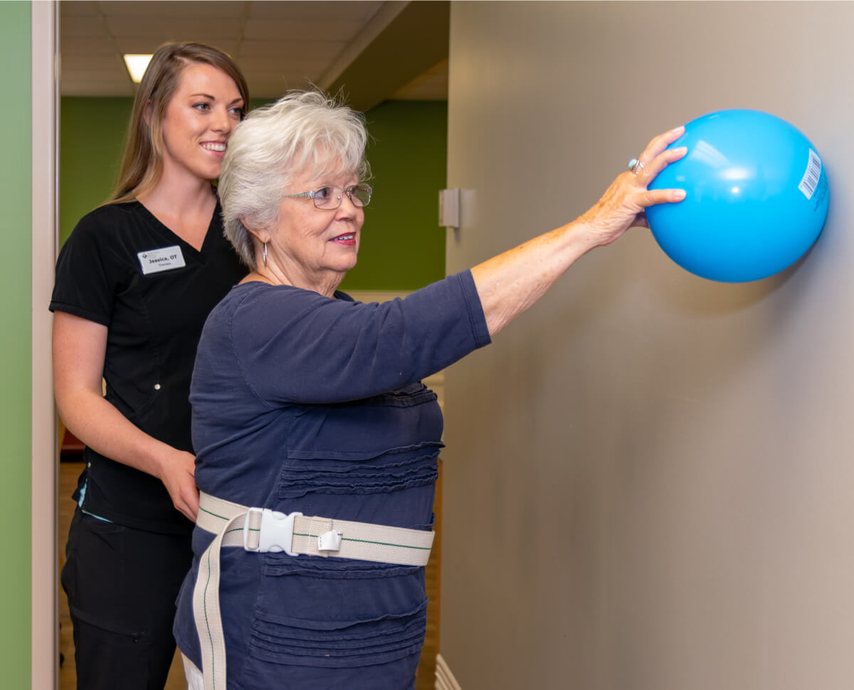 Senior balancing a ball at a rehab appointment