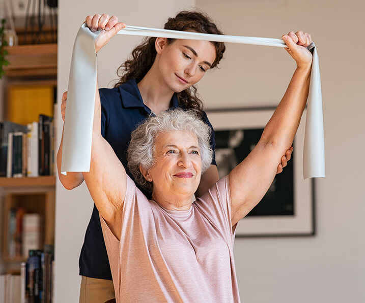 Woman using elastic band to exercise with nurse