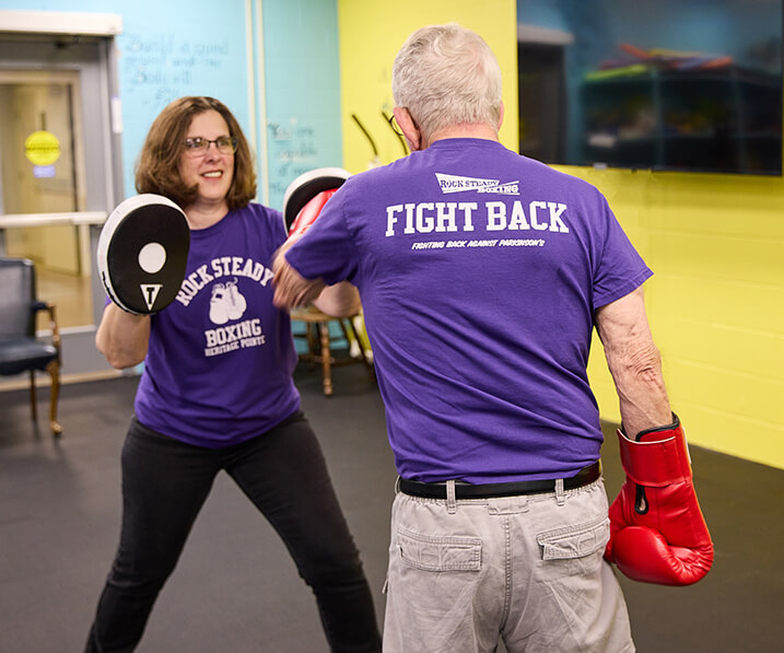 Senior man at boxing with instructor at Rock Steady Boxing gym