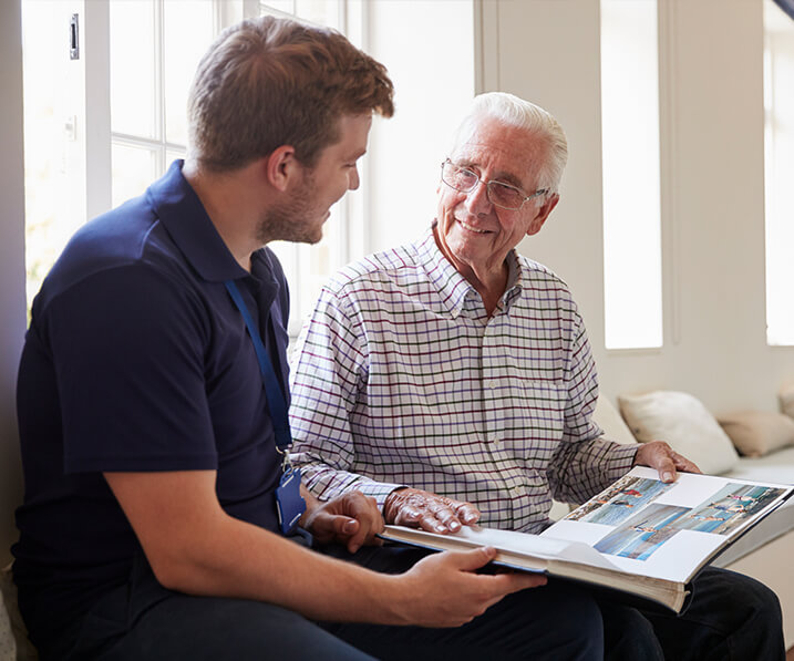 Senior looking through photo book with employee