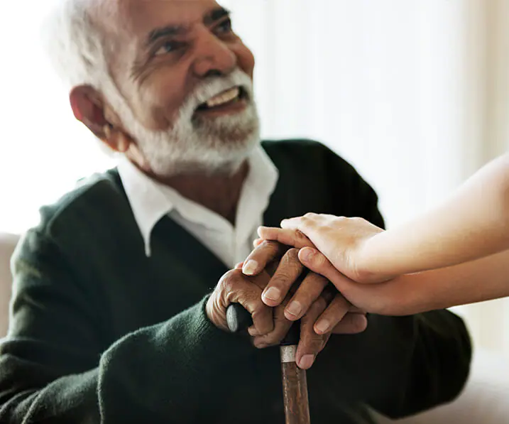 Senior man resting on his cane while looking up at an employee