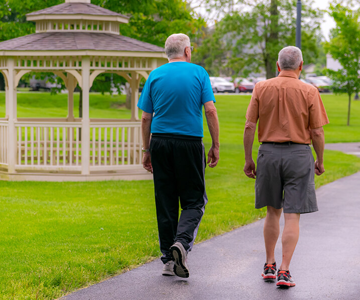 Two seniors walking by a gazebo