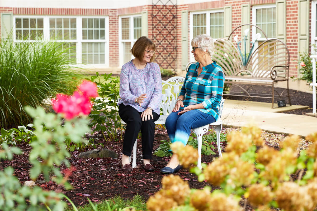 Two women talking on a garden bench