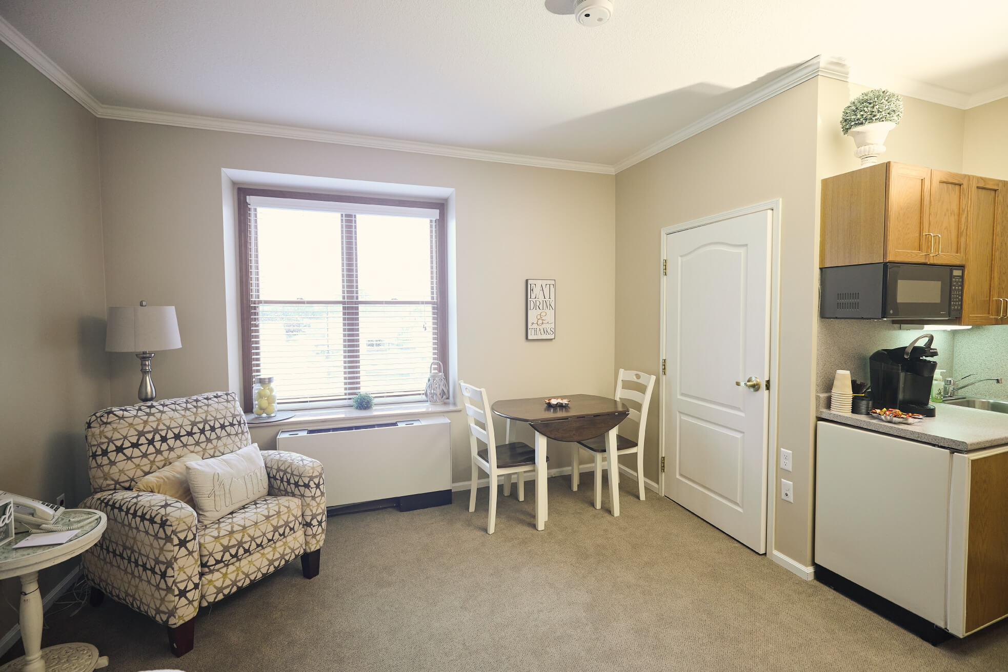 Kitchenette and couples dining table next to sitting area in room