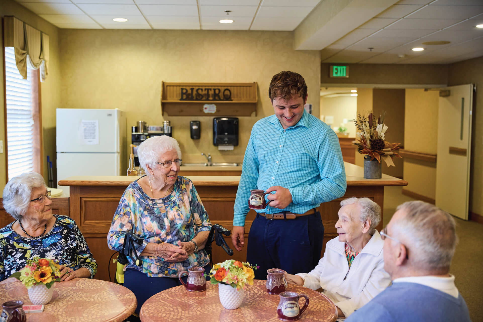 Employee talking to four residents at cafe table