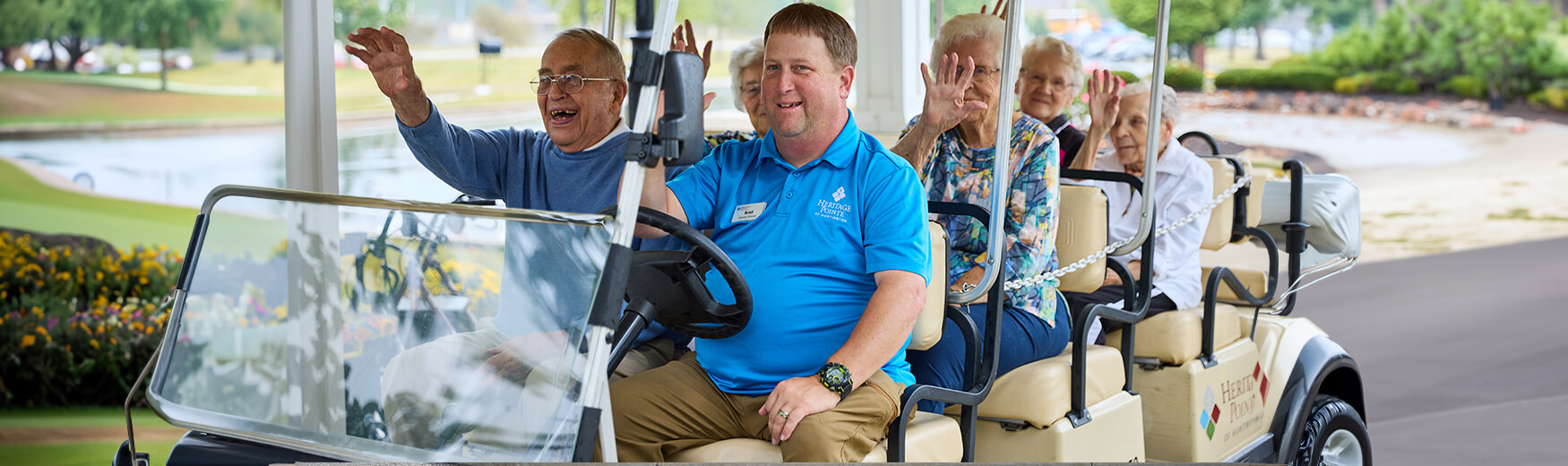 Seniors waving while driving on golf cart