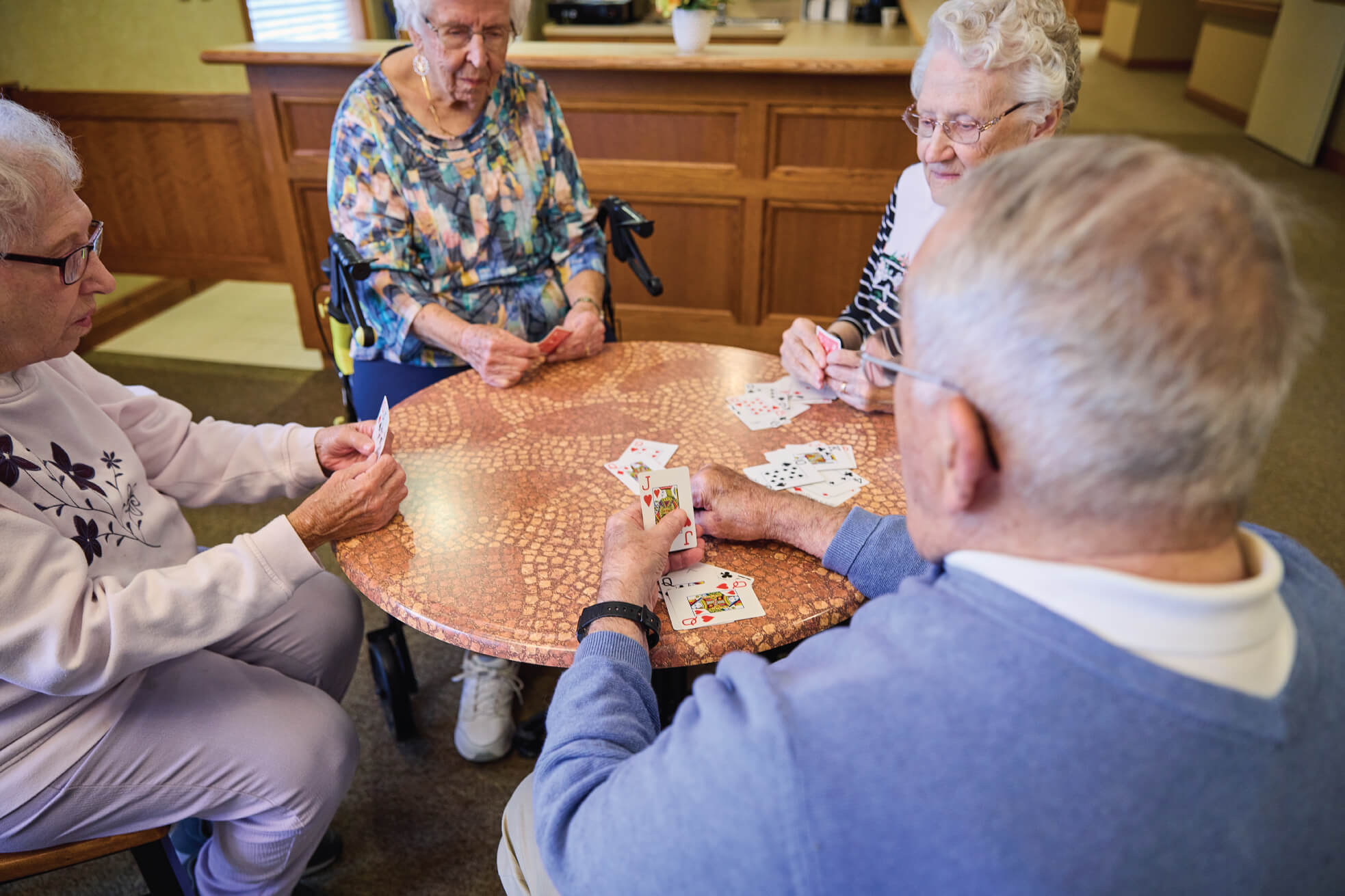 Four seniors playing cards at a table