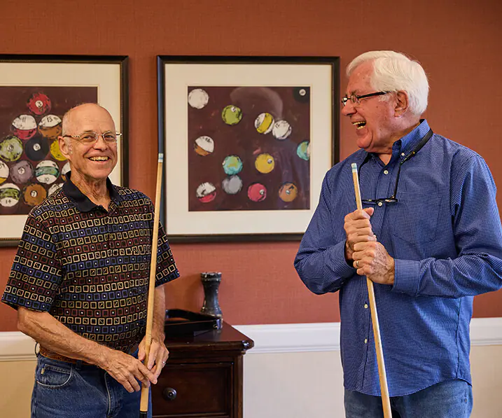 Two residents playing pool and laughing