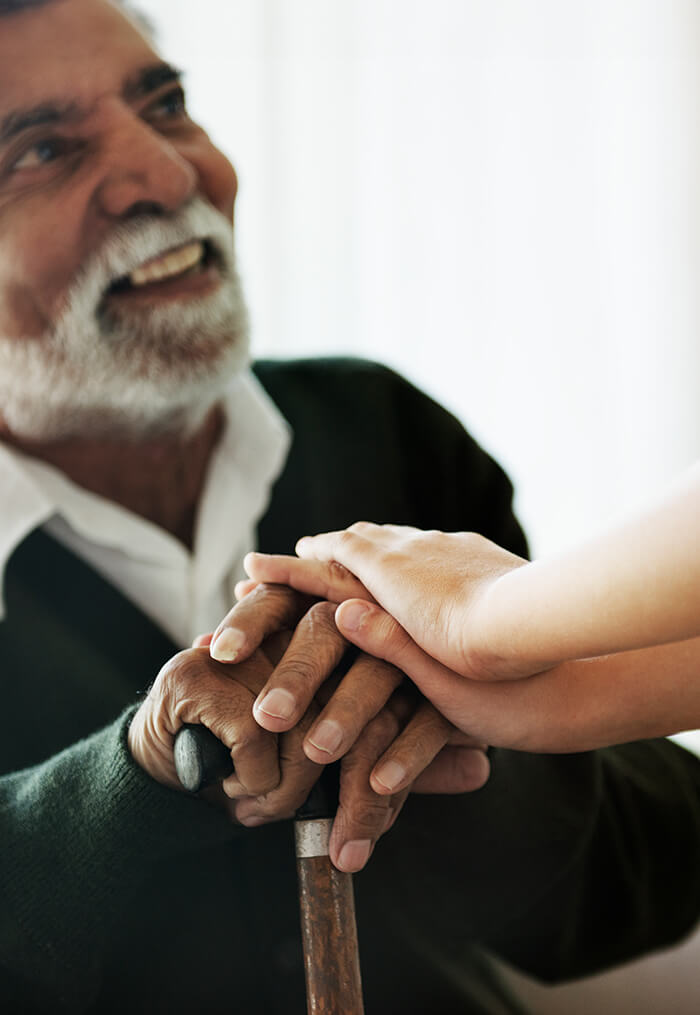 Senior man resting hands on cane with another person