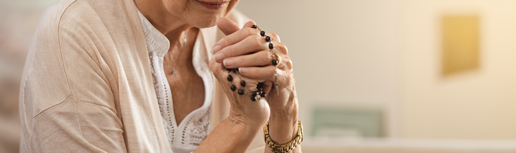 Senior woman holding rosary beads while praying