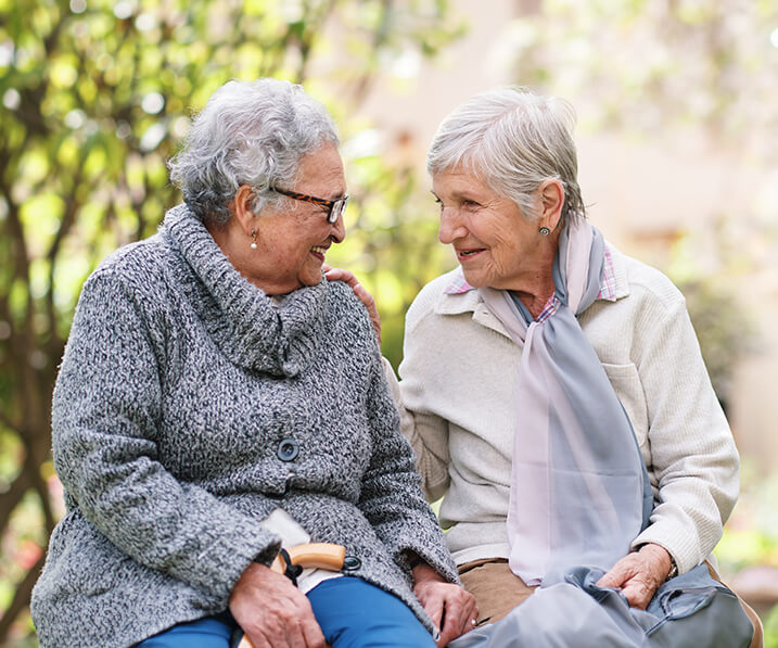 Two seniors talking on outdoor bench