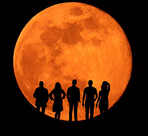 Five silhouettes in large eclipsed moon