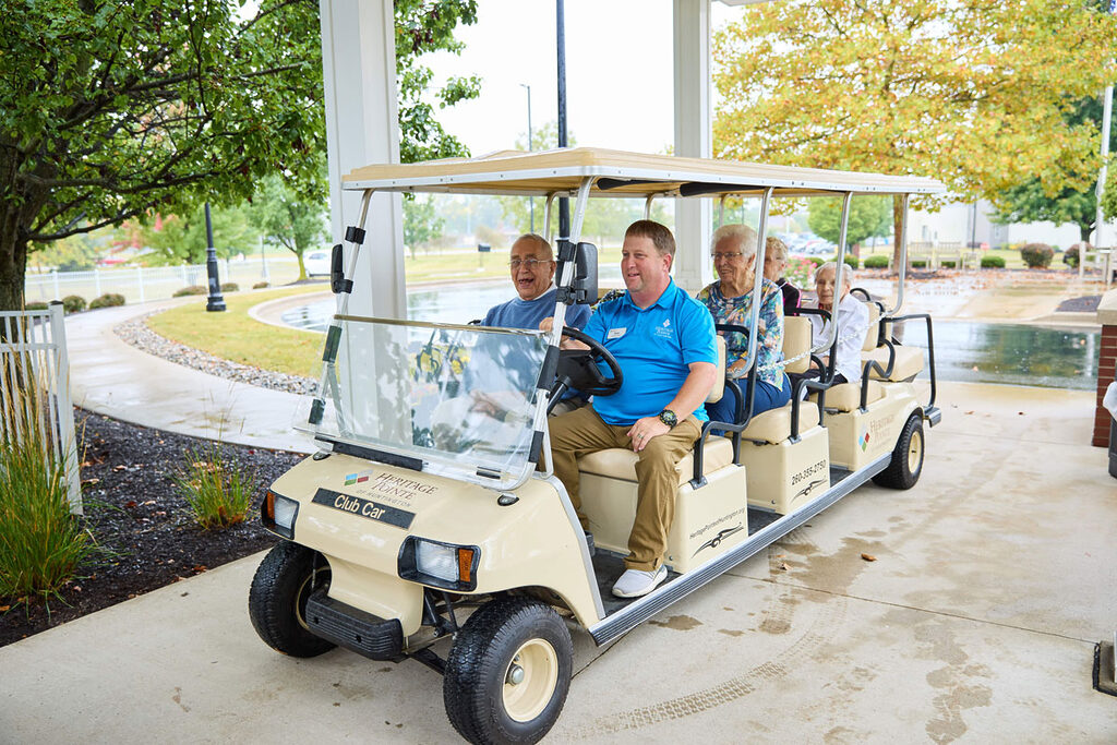 Seniors in golf cart driven by Heritage Pointe Employee