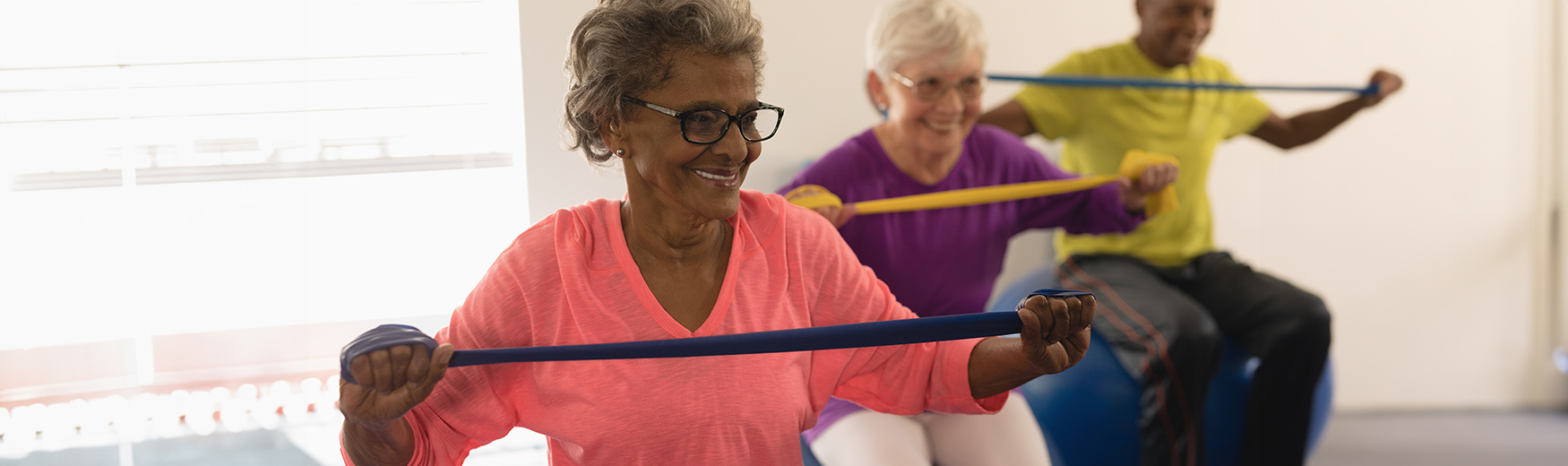 Seniors exercising with elastic bands on exercise balls