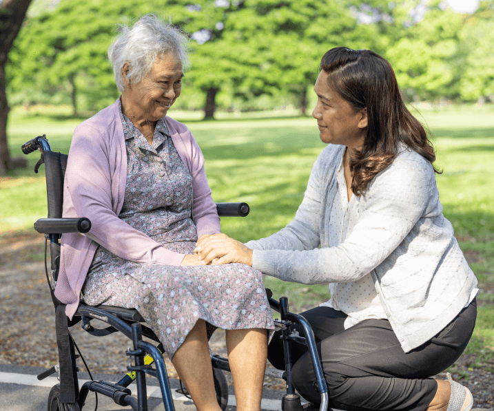 Caregiver comforting elderly woman in wheelchair outdoors