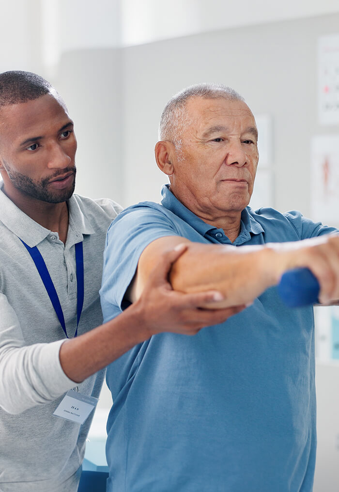 Physical therapist assisting senior man with arm exercise using a dumbbell