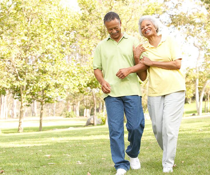 senior couple arm in arm walking through the woods