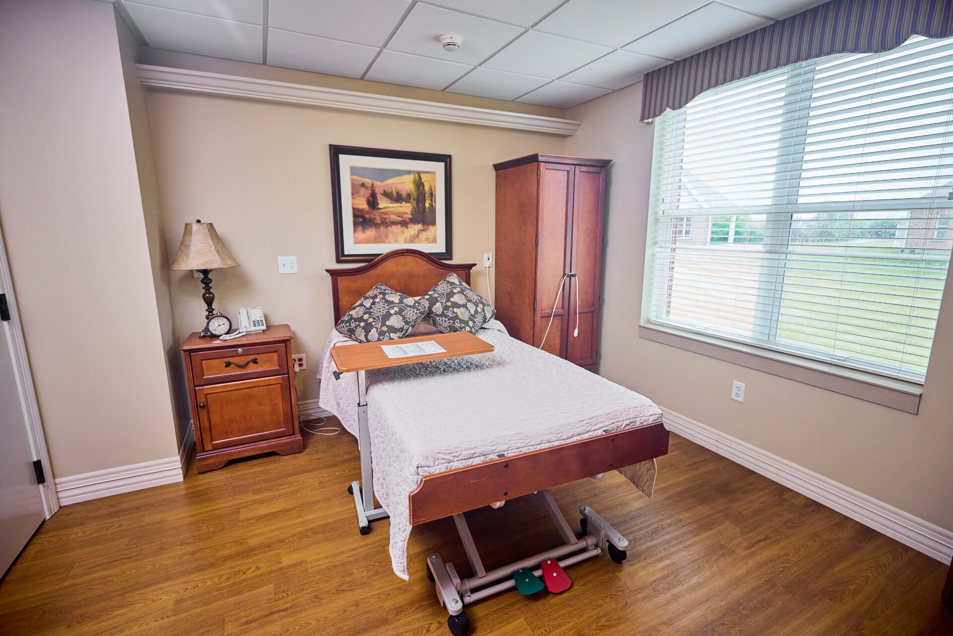 Rehabilitation suite featuring adjustable bed, bedside table and closet, and a large window