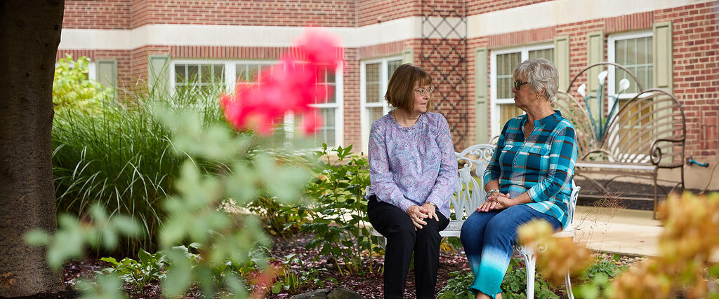 Senior women sit on a bench in a park and talk