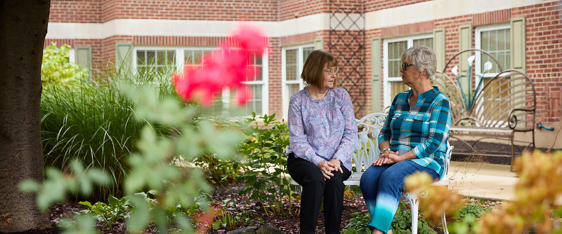 Senior women sit on a bench in a park and talk