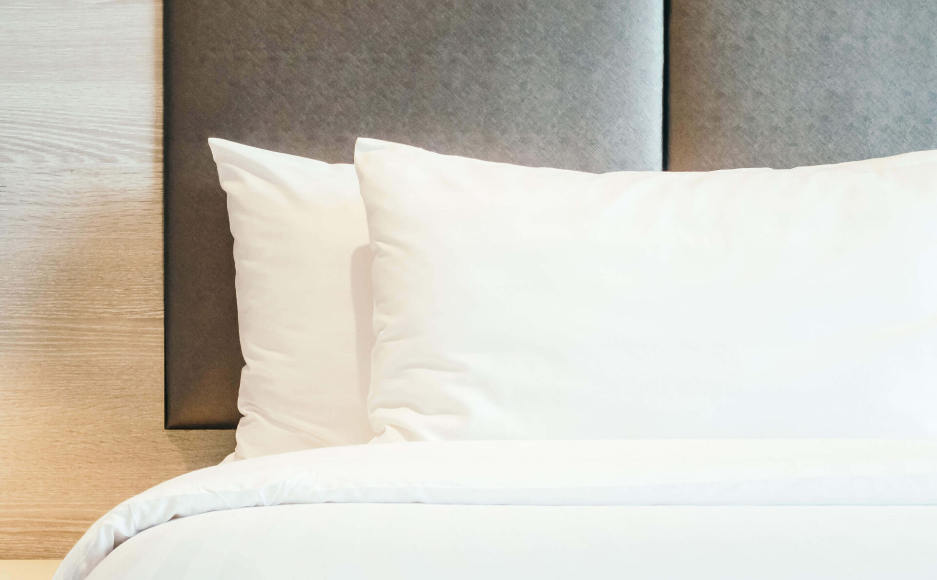 Plush pillows and white bedding on a bed in a cozy senior living unit.