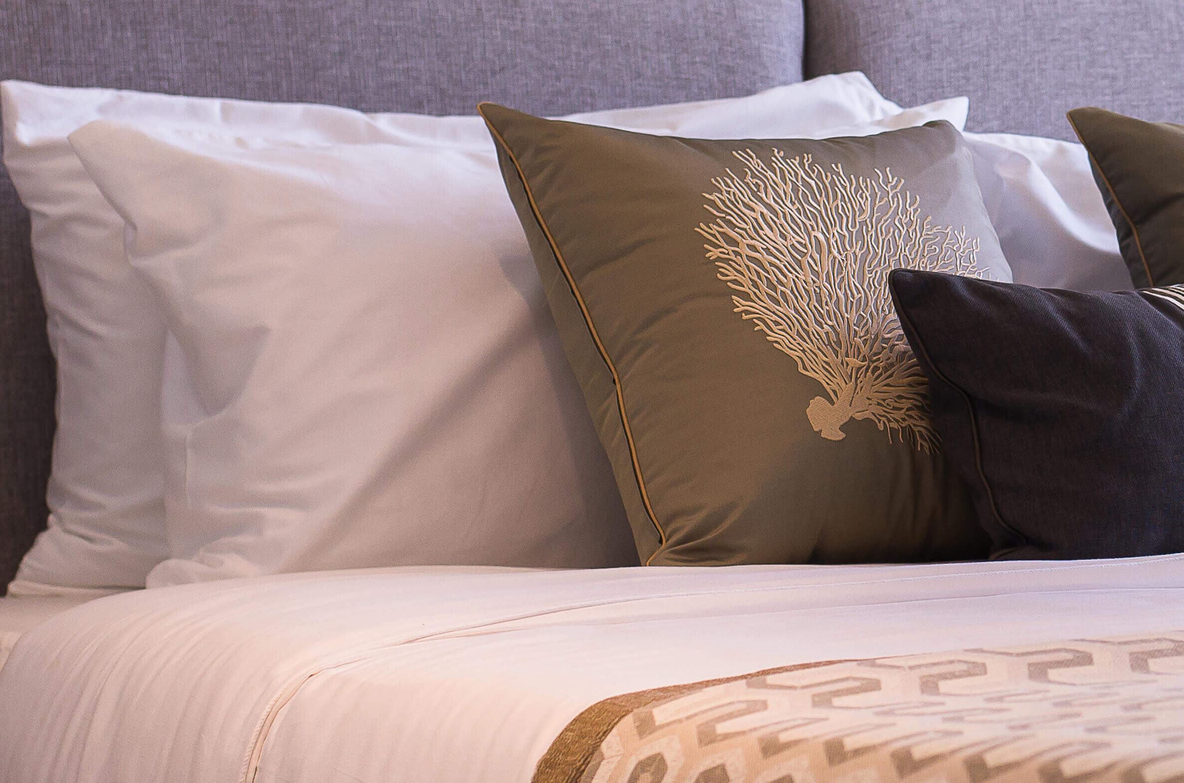 Cozy bed with white linens and decorative pillows in a senior living unit.