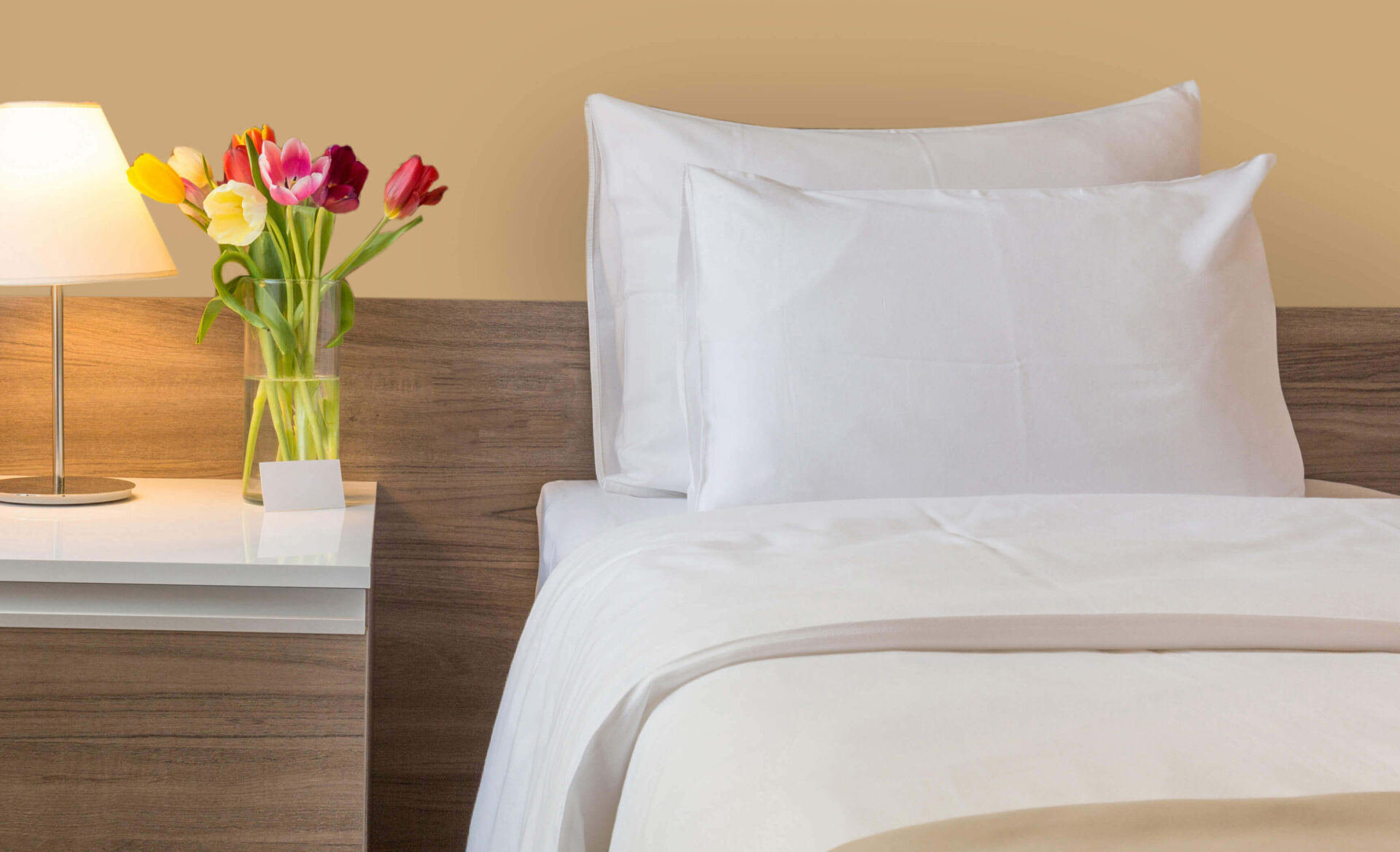 Cozy bedroom in living community with crisp white bedding and fresh tulips.