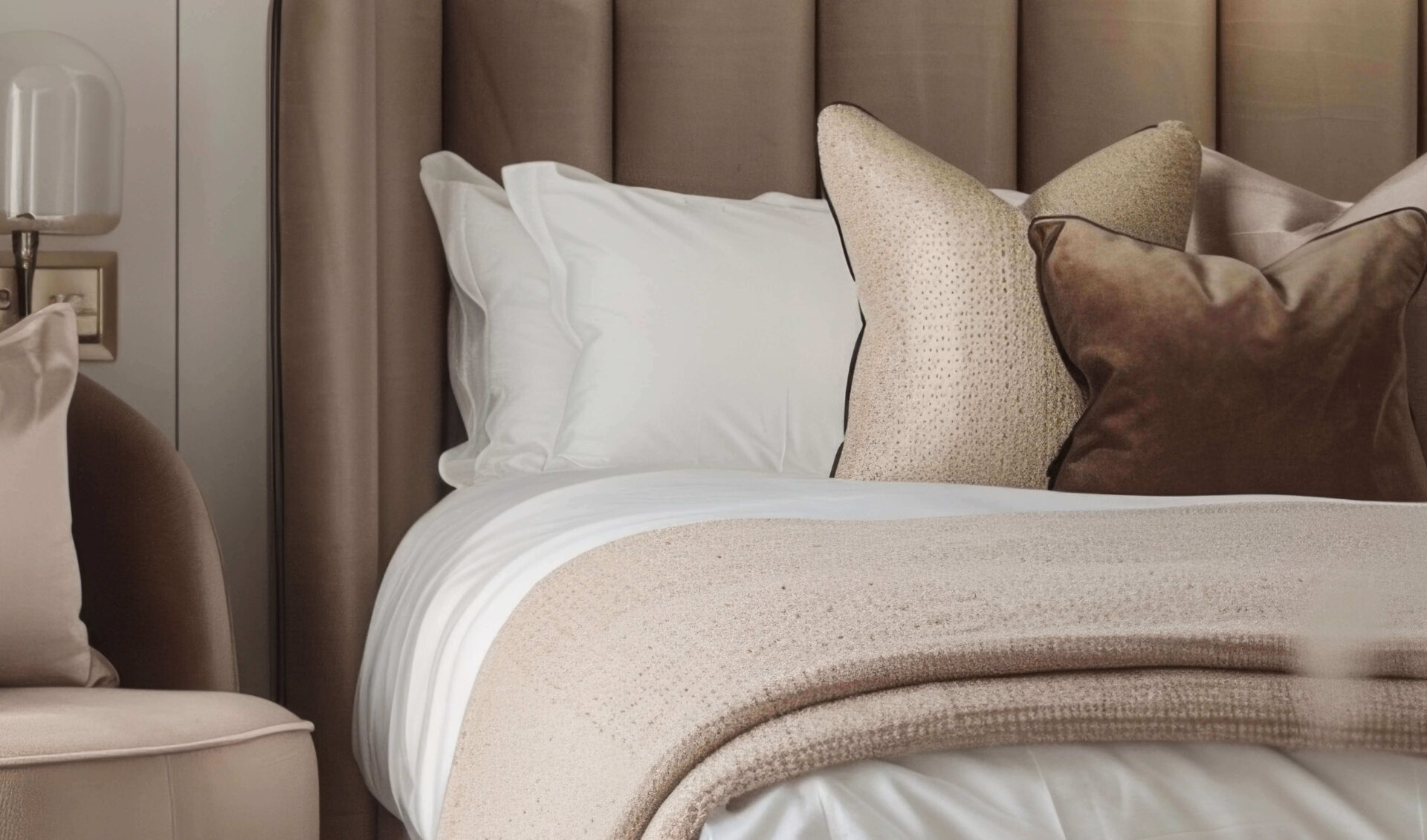 Cozy bedroom in a modern unit with plush pillows and a beige throw blanket.