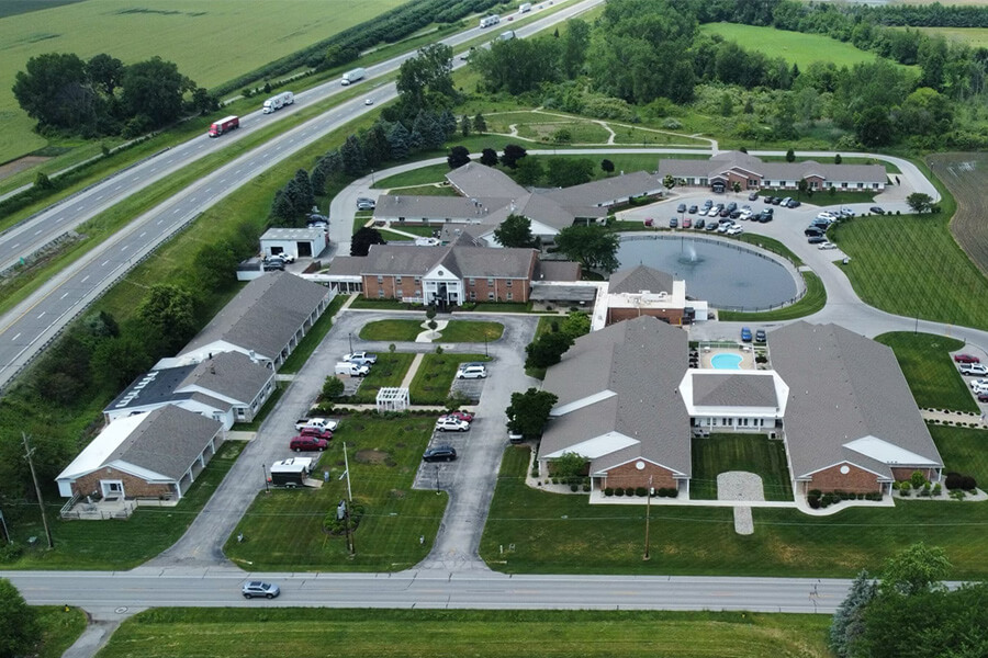Aerial view of a senior living community with multiple units, a pond, and a swimming pool.