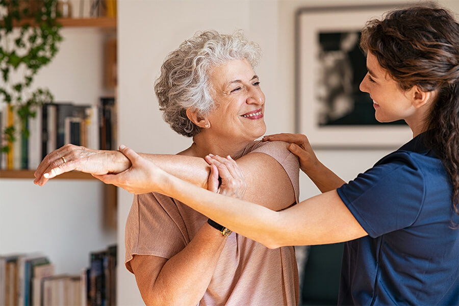 Senior woman smiling during an assisted exercise with a caregiver at a community unit.