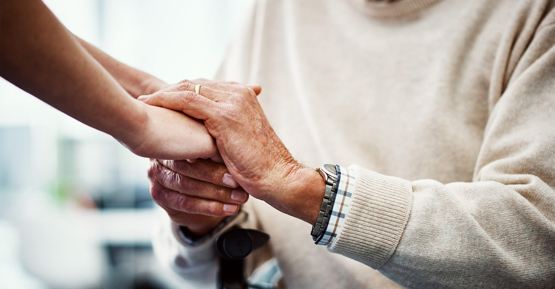Close-up of young and elderly hands clasped together, showing support and care.