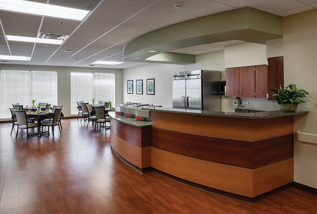 Spacious dining area in a senior living community with tables and chairs.