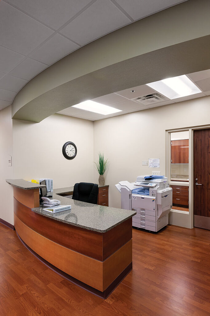 Reception desk and equipment in a well-lit nurse station with wooden flooring.
