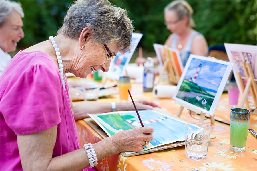 Older adults painting outdoors at art in a senior community.