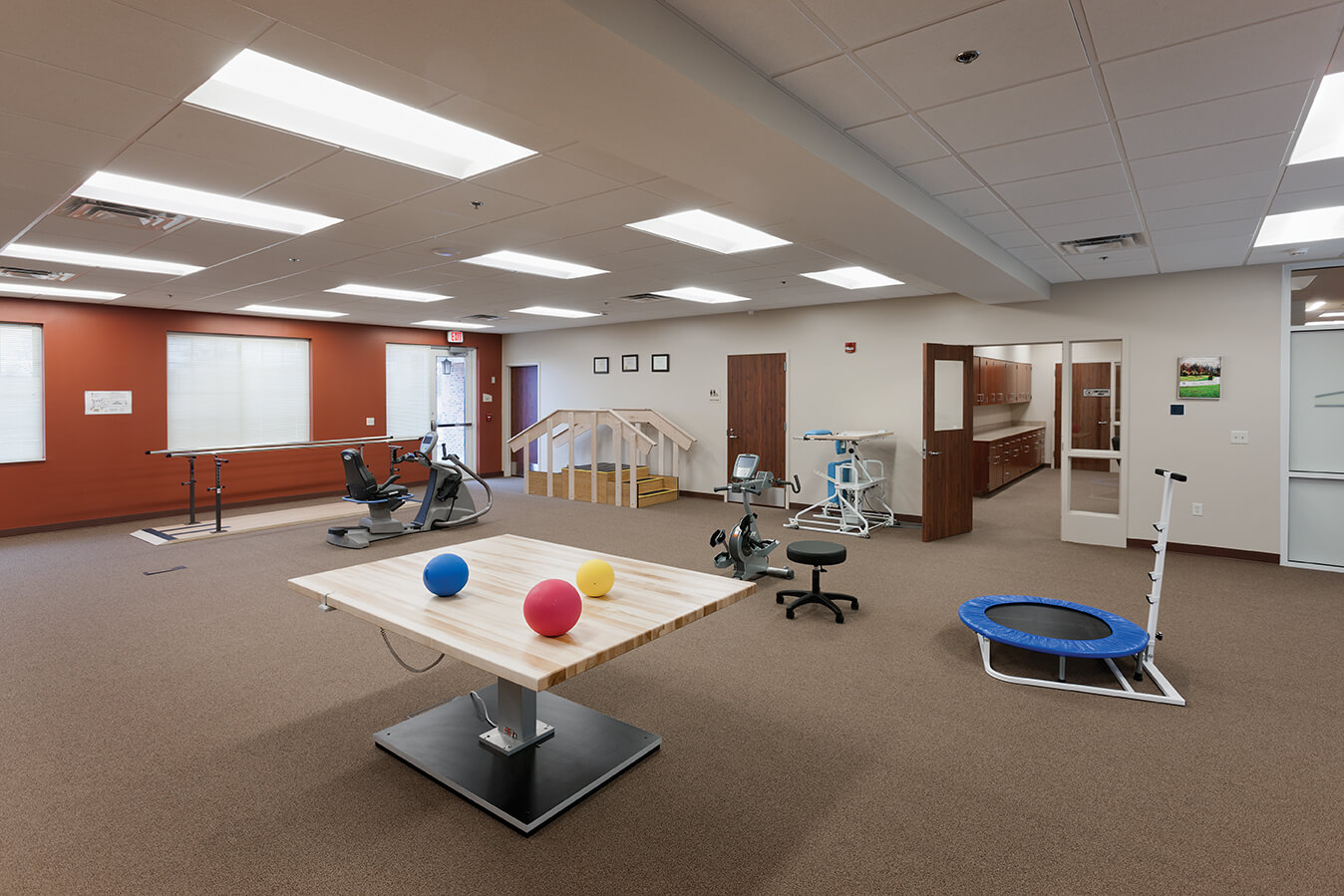 Spacious rehabilitation room with exercise equipment and therapy tools.