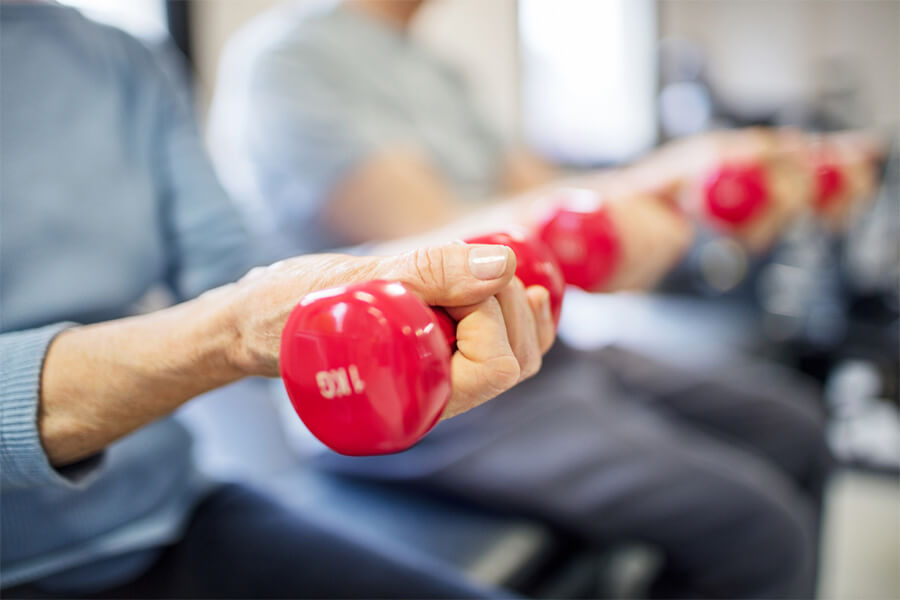 Individuals exercising with red dumbbells in a senior community fitness session.