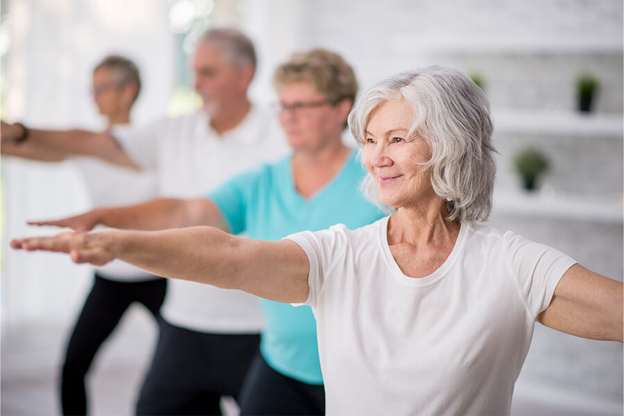 Group of seniors engaged in a fitness class, practicing yoga poses.