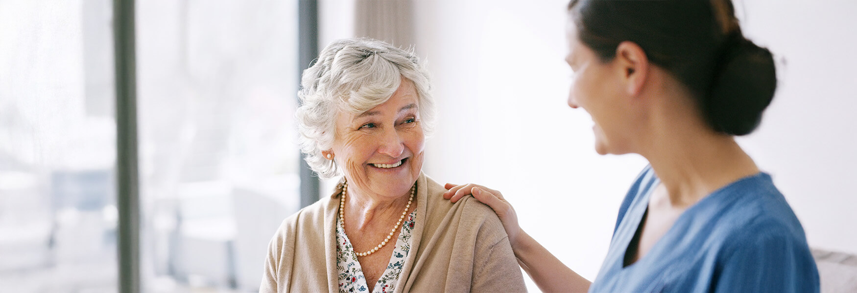Elderly woman smiling with a caregiver in a senior living community.
