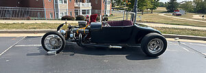 Vintage car parked in front of brick residential units with green lawn.