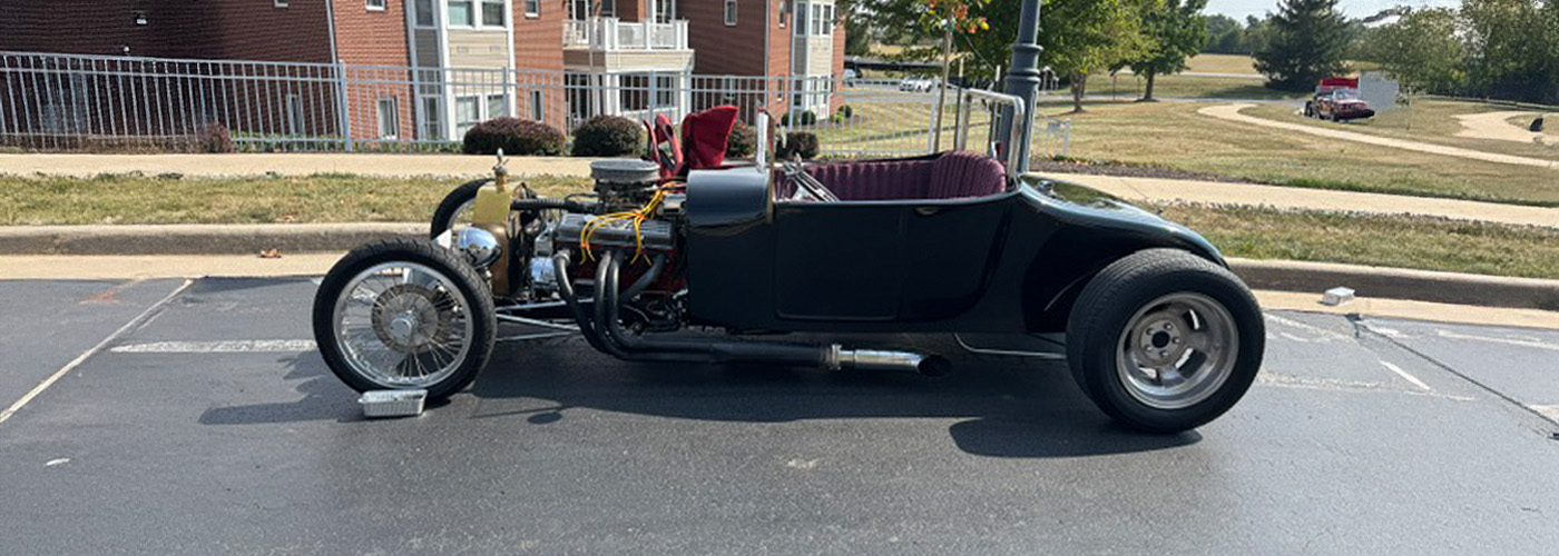 Vintage car parked in front of brick residential units with green lawn.