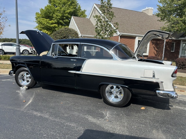 A classic 50s black and white car with hood and trunk open