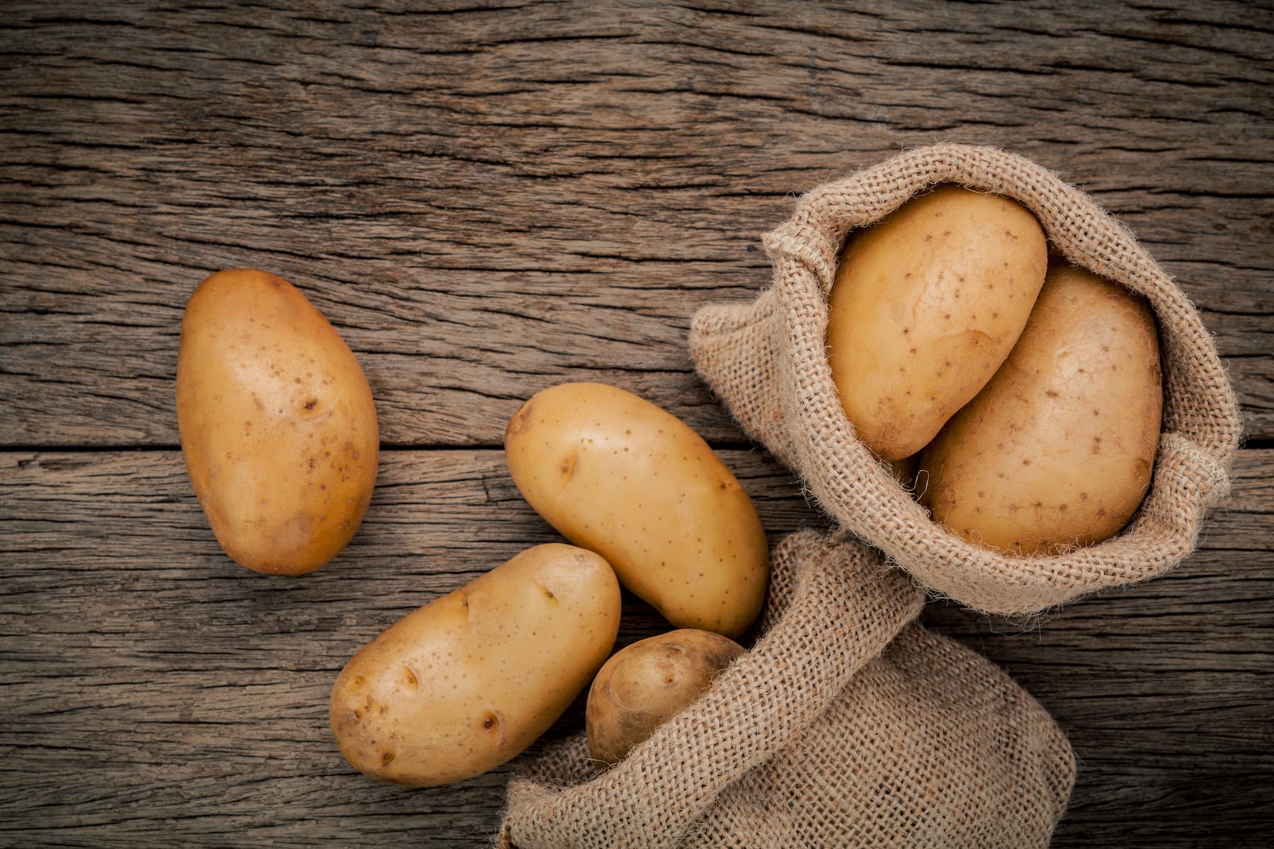 potatoes in a sack sat on a wood table