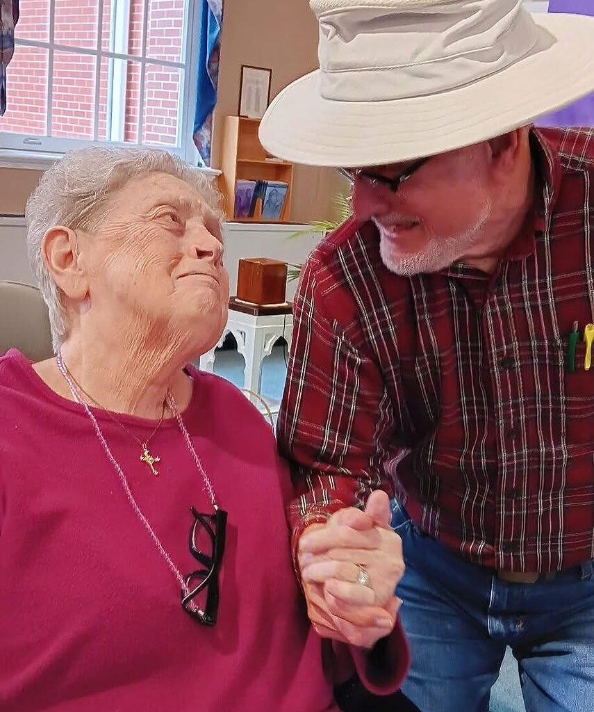 two senior residents hold hands and embrace