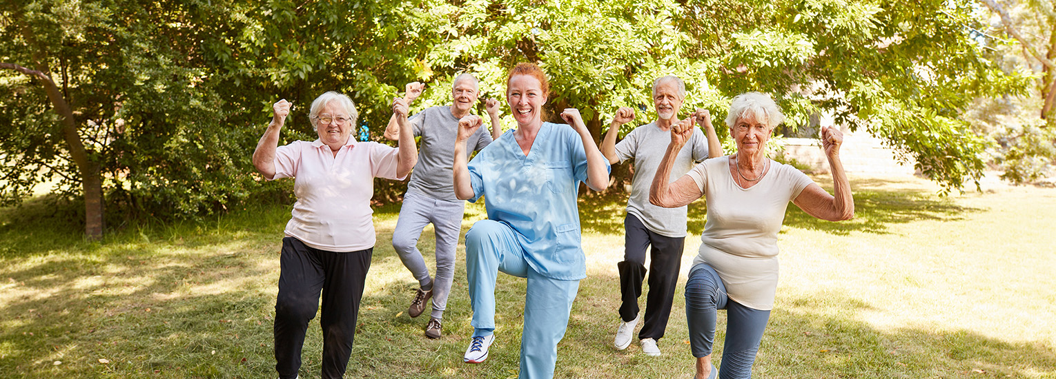 Group of seniors follow physical therapist in movement exercises outdoors