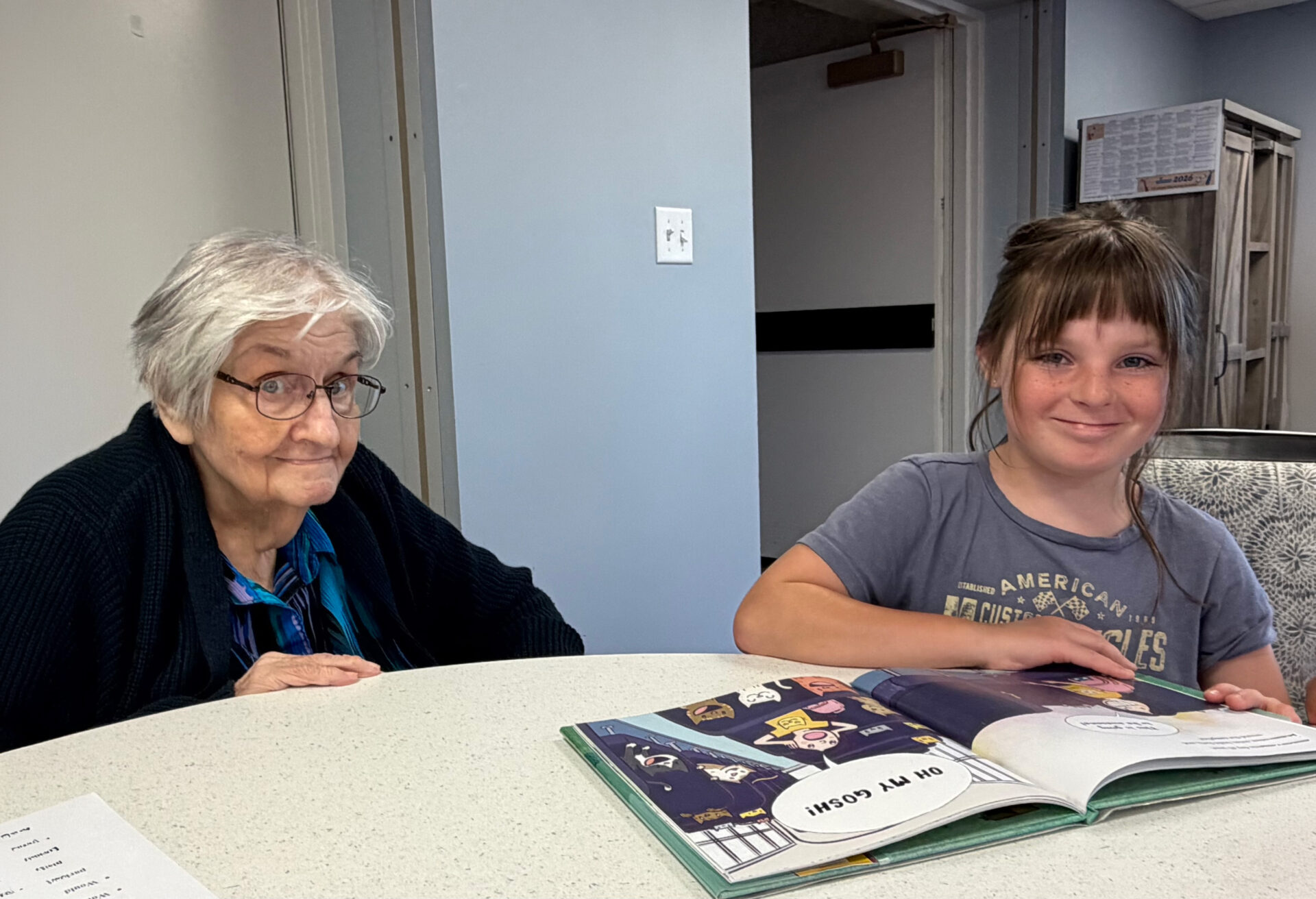 Senior woman and young girl smiling as they read a book together