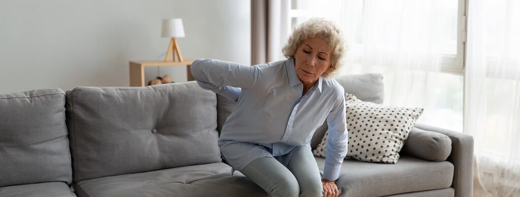 Senior woman standing up from couch